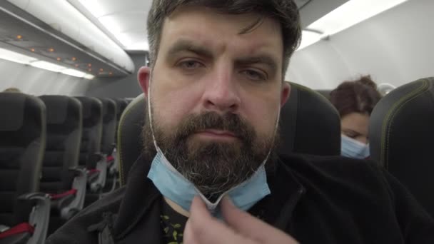 Let v letadle během pandemie koronaviru Covid-19. Maskovaný muž v letadle. Detailní záběr. — Stock video