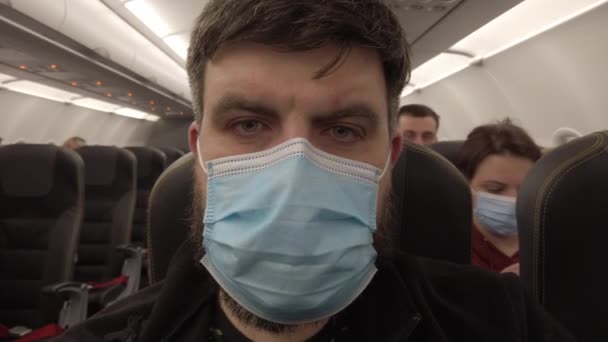 Flight in an airplane during the Covid-19 coronavirus pandemic. Masked man on the plane. Close-up. — Stock Video