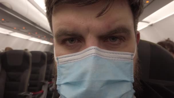 Vuelo en un avión durante la pandemia del coronavirus Covid-19. Hombre enmascarado en el avión. Primer plano. — Vídeo de stock