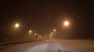 Avrupa, Kiev, Ukrayna - Şubat 2021: Bir araba kar fırtınası sırasında karla kaplı bir pistte ilerliyor. Arabadan bak. Gece yolu.