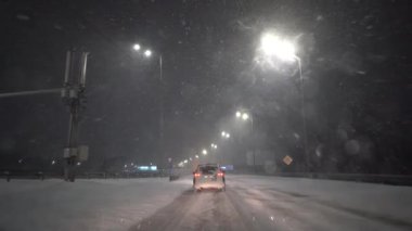 Avrupa, Kiev, Ukrayna - Şubat 2021: Bir araba kar fırtınası sırasında karla kaplı bir pistte ilerliyor. Arabadan bak. Gece yolu.