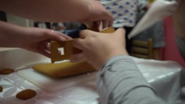 Çocuklar anneleriyle birlikte zencefilli kek evi hazırlıyorlar. Zencefilli kurabiye evi, yemek pişirme. El yapımı..