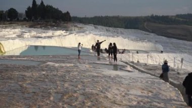 Pamukkale, Türkiye - Ocak 2021: Turistler Pamukkale 'deki termal yaylar boyunca yürüyorlar. Gün batımı
