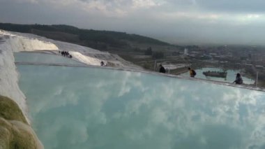 Pamukkale, Türkiye - Ocak 2021: Turistler Pamukkale 'deki termal yaylar boyunca yürüyorlar. Gün batımı
