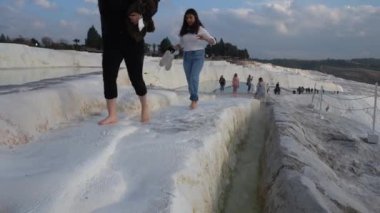 Pamukkale, Türkiye - Ocak 2021: Turistler Pamukkale 'deki termal yaylar boyunca yürüyorlar. Gün batımı