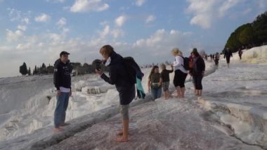 Pamukkale, Türkiye - Ocak 2021: Turistler Pamukkale 'deki termal yaylar boyunca yürüyorlar. Gün batımı