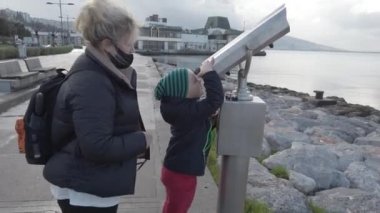 İzmir, Türkiye - Ocak 2021: Bir kız limandaki dürbünlerden bakıyor. Turist dürbünü.