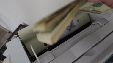 Banknotlar için sayma makinesi. Hesap makinesindeki dolarlar. Dolar banknotlarının yeniden hesaplanması. Amerikan doları banknotlar için bir makine tarafından sayılır..