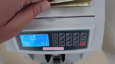Banknotlar için sayma makinesi. Hesap makinesindeki dolarlar. Dolar banknotlarının yeniden hesaplanması. Amerikan doları banknotlar için bir makine tarafından sayılır..