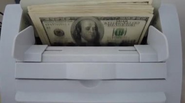 Banknotlar için sayma makinesi. Hesap makinesindeki dolarlar. Dolar banknotlarının yeniden hesaplanması. Amerikan doları banknotlar için bir makine tarafından sayılır..