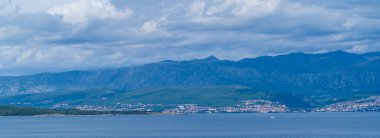 KRK Adası, Vrbnik, Hırvatistan - 19 Nisan 2025: Şehir manzarası. Kıyı şeridi, kayalık sahil ve dağlar görünüyor..