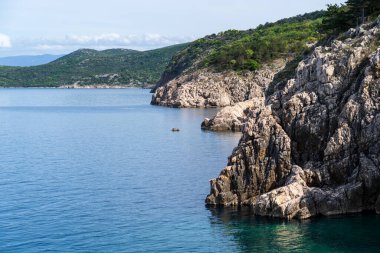 KRK Adası, Vrbnik, Hırvatistan - 19 Nisan 2025: Şehir manzarası. Kıyı şeridi, kayalık sahil ve dağlar görünüyor..