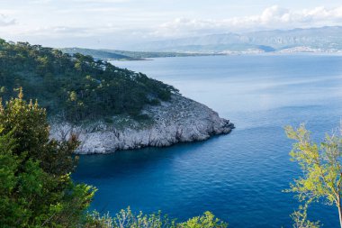 KRK Adası, Vrbnik, Hırvatistan - 19 Nisan 2025: Şehir manzarası. Kıyı şeridi, kayalık sahil ve dağlar görünüyor..