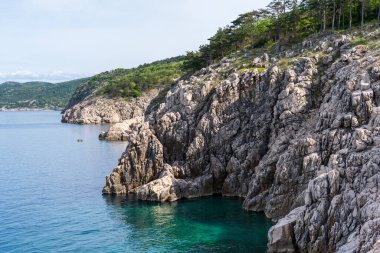 KRK Adası, Vrbnik, Hırvatistan - 19 Nisan 2025: Şehir manzarası. Kıyı şeridi, kayalık sahil ve dağlar görünüyor..