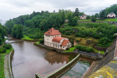 Bila Tremesna, Czech Republic - July 27, 2025: Scenic view of the Les Kralovstvi dam with fairy tale towers on the Elbe river. Beautiful landscape of historic architecture, green forest, and stone bridge.
