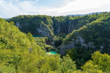 Plitvice Gölleri, Hırvatistan - 16 Ağustos 2025: Ulusal Park 'taki turkuaz göl ve şelalelerin manzaralı manzarası. Yeşillik orman ve kireçtaşı kayalıkları olan UNESCO Dünya Mirası.