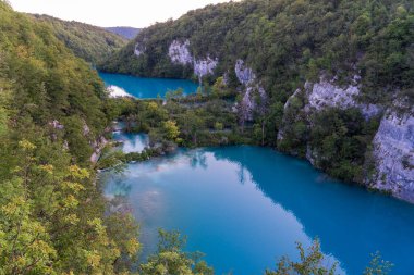 Plitvice Gölleri, Hırvatistan - 16 Ağustos 2025: Ulusal Park 'taki turkuaz göl ve şelalelerin manzaralı manzarası. Yeşillik orman ve kireçtaşı kayalıkları olan UNESCO Dünya Mirası.