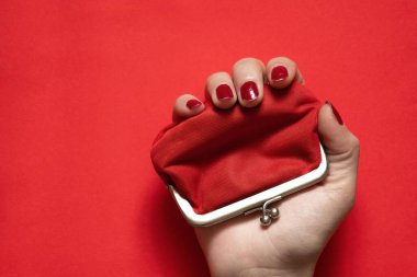 İzole edilmiş arka planda kırmızı eski cüzdan ve kadın eli.