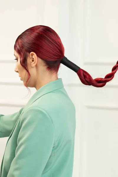 Jovem com cabelo vermelho com maquiagem e em uma jaqueta verde, vista lateral em uma cauda longa de cabelo — Fotografia de Stock