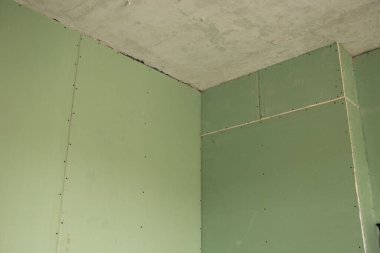 Yenileme sırasında odada yeşil alçıpan duvar, apartman yenileme, arka plan olarak alçı taşı.