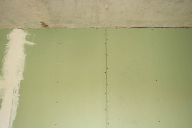 Yenileme sırasında odada yeşil alçıpan duvar, apartman yenileme, arka plan olarak alçı taşı.