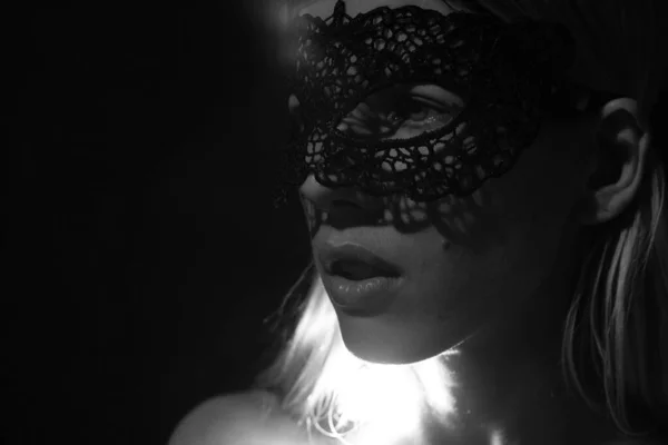 face of a girl in a black lace mask in the dark under low light close up