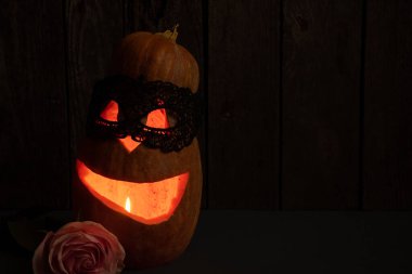 Cadılar Bayramı balkabağı gülüşü ve parti için korkunç gözler. Korkunç Cadılar Bayramı balkabağının yakından görüntüsü, gözleri ve gülün yanında, karanlıkta mumlar.