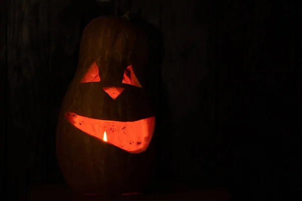 Halloween pumpkin smile and scary eyes for a party. Close up view of scary halloween pumpkin with eyes glowing inside on black background