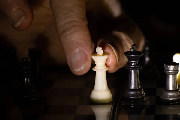 old woman\'s hand and chess in the dark, playing chess