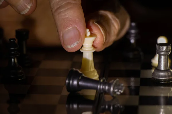 old woman\'s hand and chess in the dark, playing chess