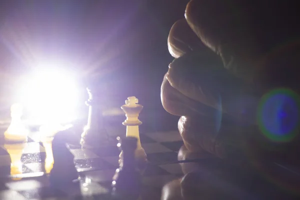 old woman\'s hand and chess in the dark, playing chess