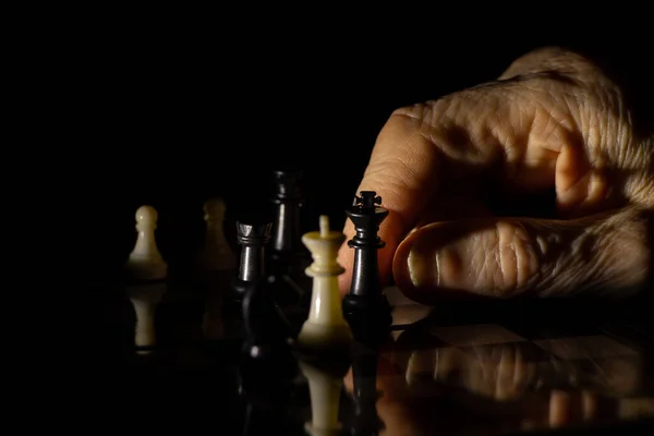 old woman\'s hand and chess in the dark, playing chess