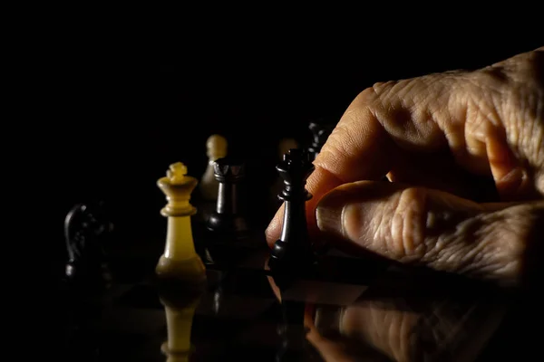 old woman\'s hand and chess in the dark, playing chess