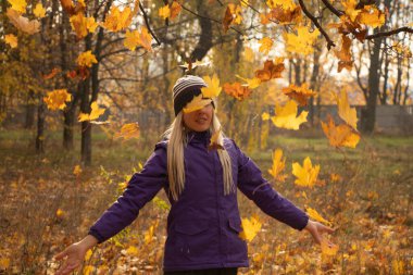Sonbahar parkında sarı yapraklar içinde gün boyunca Ukrayna 'da düşen bir kız.