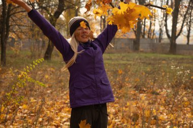 Sonbahar parkında sarı yapraklar içinde gün boyunca Ukrayna 'da düşen bir kız.