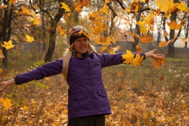 Sonbahar parkında sarı yapraklar içinde gün boyunca Ukrayna 'da düşen bir kız.