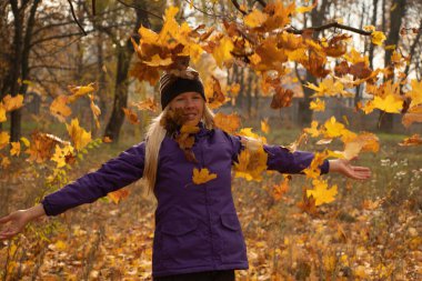 Sonbahar parkında sarı yapraklar içinde gün boyunca Ukrayna 'da düşen bir kız.