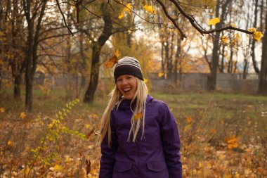 Sonbahar parkında sarı yapraklar içinde gün boyunca Ukrayna 'da düşen bir kız.