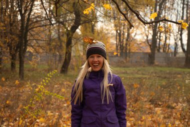 Sonbahar parkında sarı yapraklar içinde gün boyunca Ukrayna 'da düşen bir kız.
