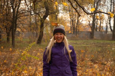 Sonbahar parkında sarı yapraklar içinde gün boyunca Ukrayna 'da düşen bir kız.