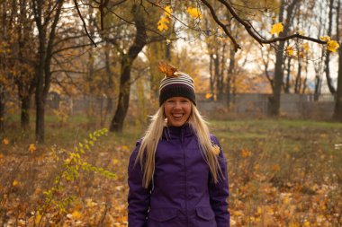 Sonbahar parkında sarı yapraklar içinde gün boyunca Ukrayna 'da düşen bir kız.