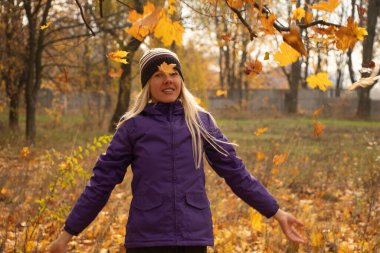 Sonbahar parkında sarı yapraklar içinde gün boyunca Ukrayna 'da düşen bir kız.