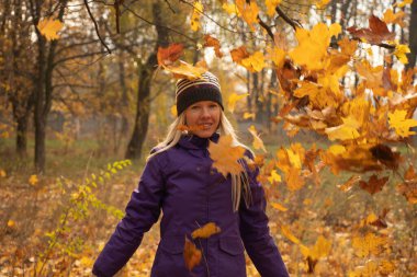 Sonbahar parkında sarı yapraklar içinde gün boyunca Ukrayna 'da düşen bir kız.