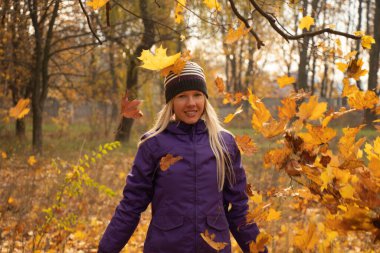 Sonbahar parkında sarı yapraklar içinde gün boyunca Ukrayna 'da düşen bir kız.