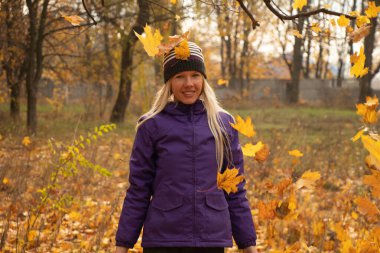 Sonbahar parkında sarı yapraklar içinde gün boyunca Ukrayna 'da düşen bir kız.