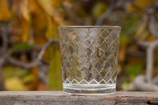 街上的一张用黄叶做的木制桌子上 放着一只装酒精饮料的空玻璃杯 — 图库照片