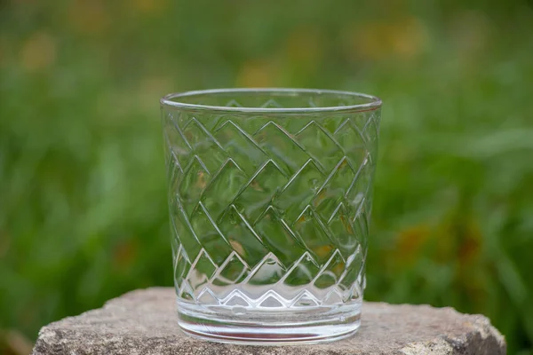 街上的草地上 一只空玻璃杯里的酒精饮料倒立在一块石头上 — 图库照片