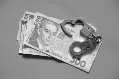 500 hrn lie next to handcuffs on an isolated background, finance and corruption clipart