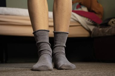 Mavi çoraplı ayaklar, gri bir halı, bir apartman dairesi, evde bir gün tatil.