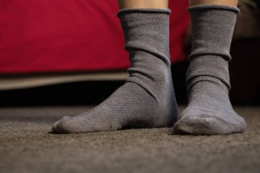 Mavi çoraplı ayaklar, gri bir halı, bir apartman dairesi, evde bir gün tatil.